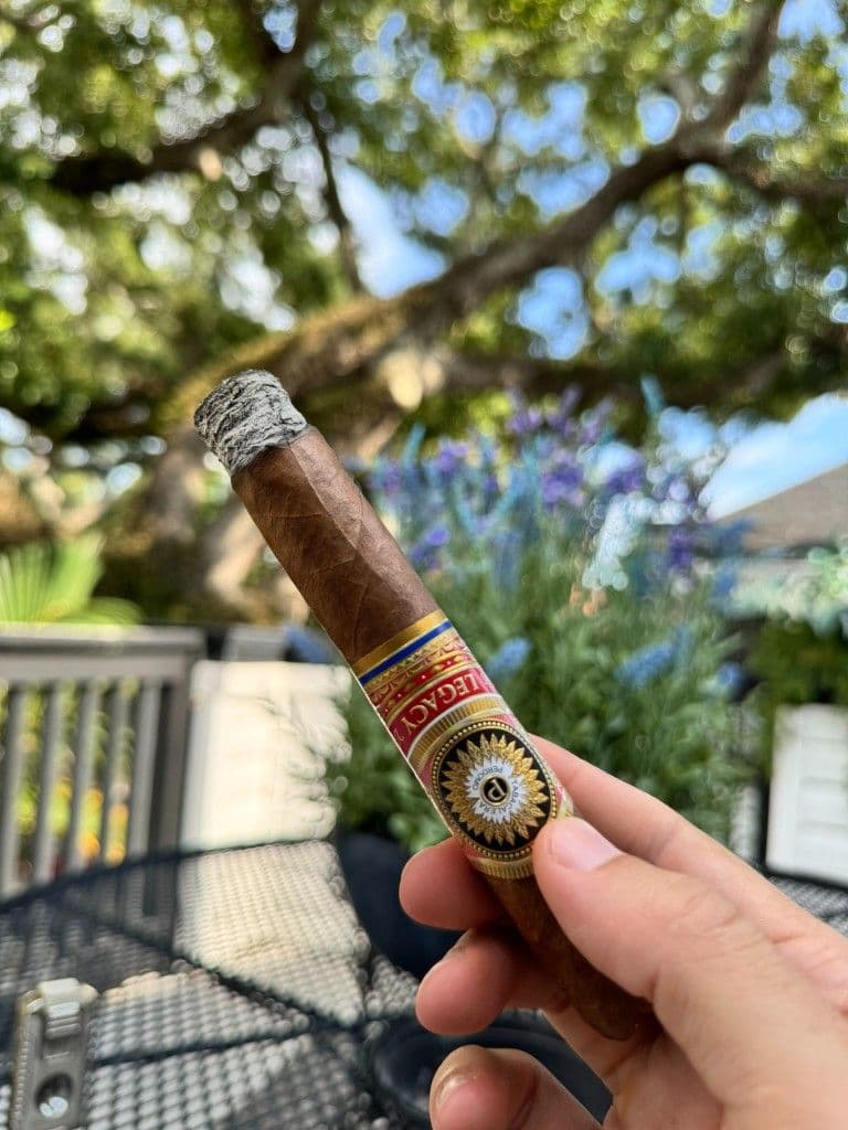 Lit Perdomo Legacy Nicaraguan Shade Grown with firm ash against lavender flowers