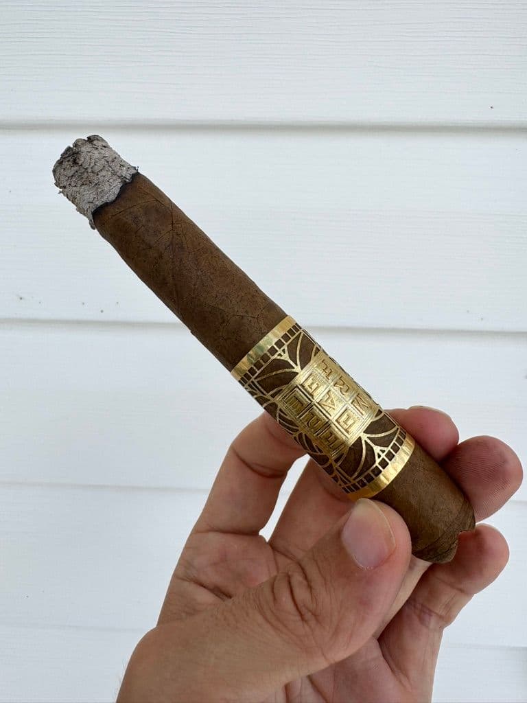 Lit Meerapfel Richard held mid-smoke showing gold band and early ash