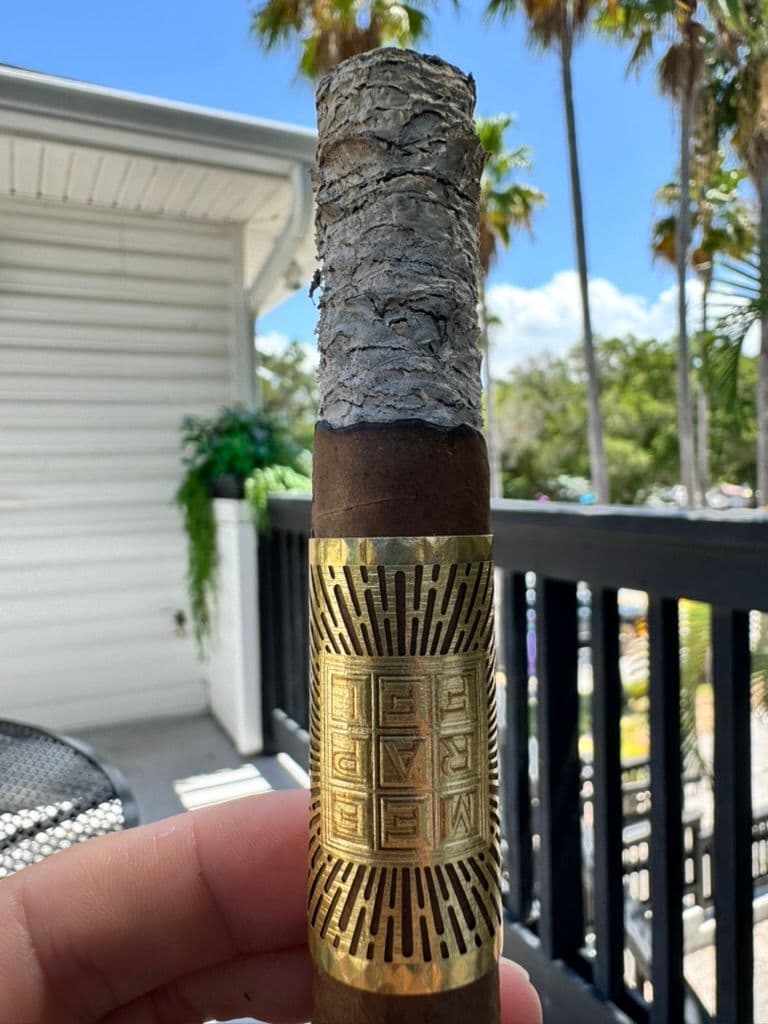 Meerapfel Meir Pyramid mid-smoke on a balcony with palm trees behind